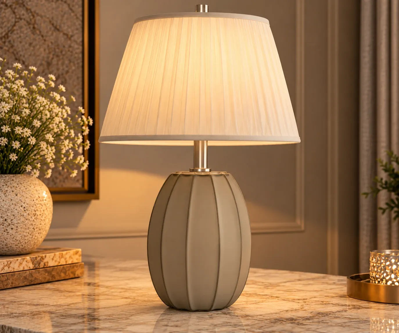 Luxury matte grey ribbed table lamp with an oval-shaped base, ivory pleated fabric shade and metallic accents, displayed on a marble tabletop.